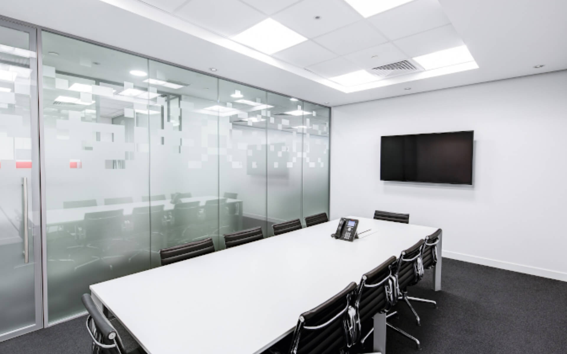 Corporate meeting room with a large table and ten chairs with a frosted glass wall